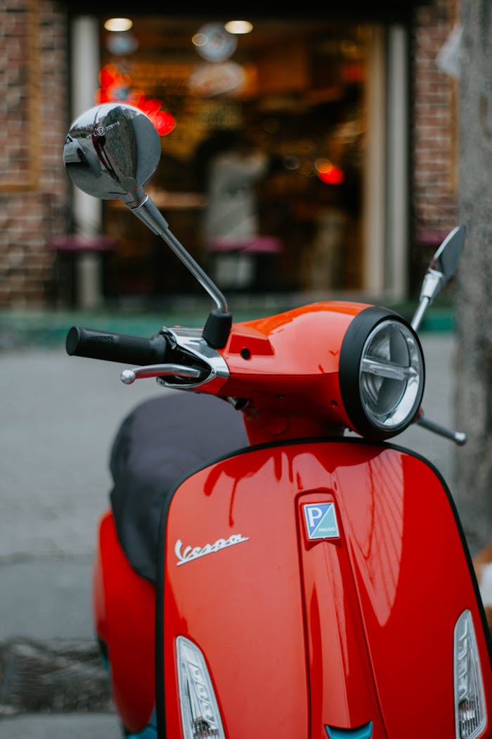 about-us-01 A vibrant red Vespa scooter parked outdoors on a street in Istanbul, capturing urban life.